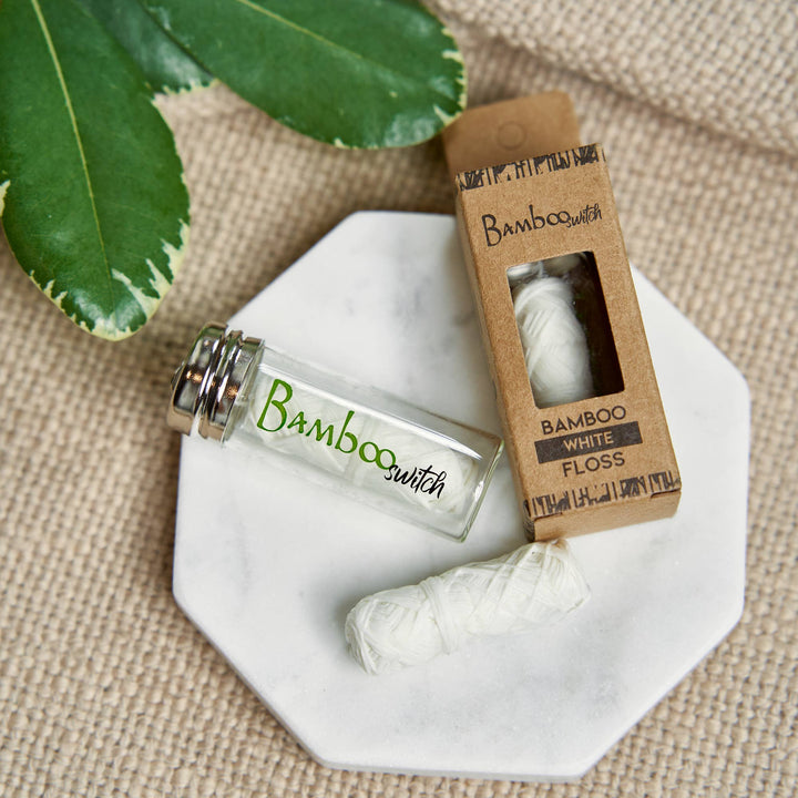 White bamboo floss yarn on a plate with glass vial and carton pack