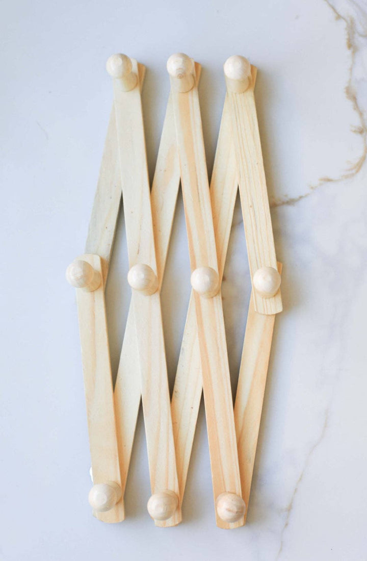 Wall-mounted wooden coat rack with multiple angled hooks and round pegs