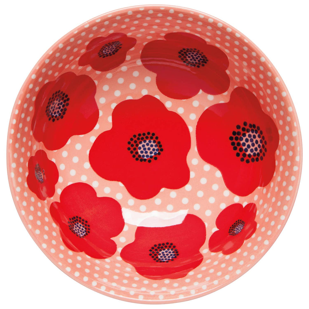 Top view of white bowl with pink interior and red poppy with dot pattern