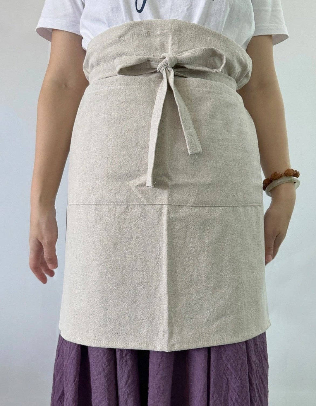 Light gray linen half apron with front pocket, waist tie, and straight skirt panel