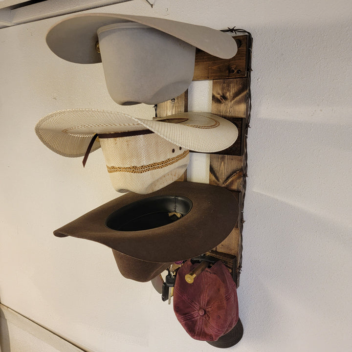 Wall-mounted hat organizer with three hanging hats and visible wood slat backing