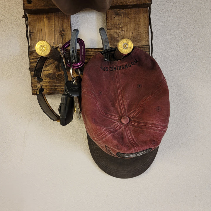 Close-up of burgundy cap and clips on wood wall-hanging hat organizer
