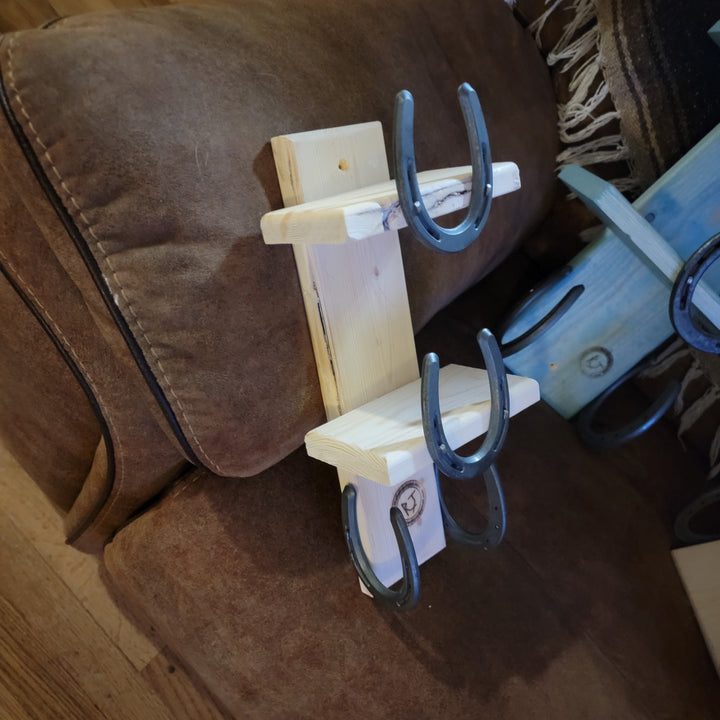 Wood towel rack with three blue horseshoe towel holders on brackets