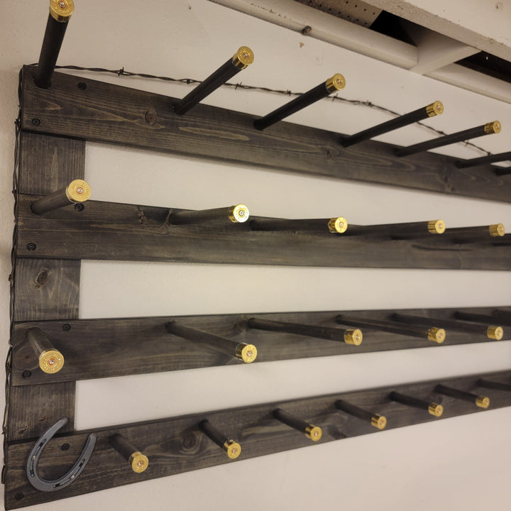 Close-up of horizontal wall organizer with dark slats, brass pegs, and hanging bar