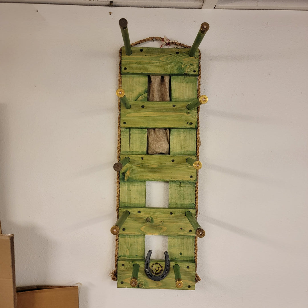 Green vertical wall hanging organizer with open slots and mounted metal horseshoe