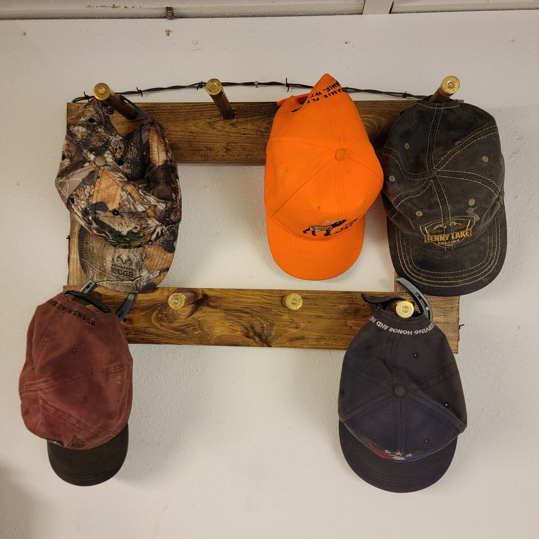 Vertical wall-hanging ball cap organizer with five assorted caps, on rustic wood rails