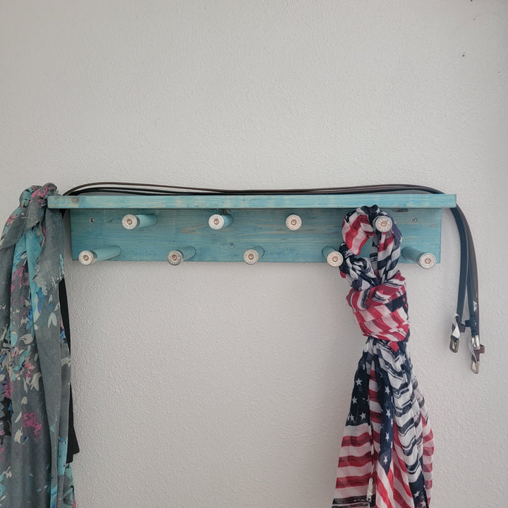 Blue scarf rack with shelf and rotating pegs, holding patterned scarves