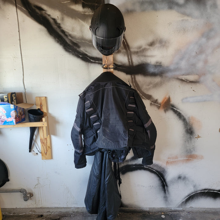 Wall-mounted motorcycle gear rack holding a black helmet and hanging jacket