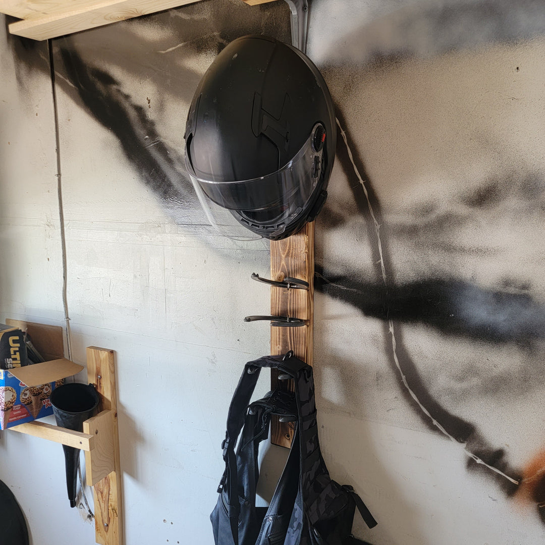 Wall-mounted motorcycle helmet rack with black helmet and hanging jacket