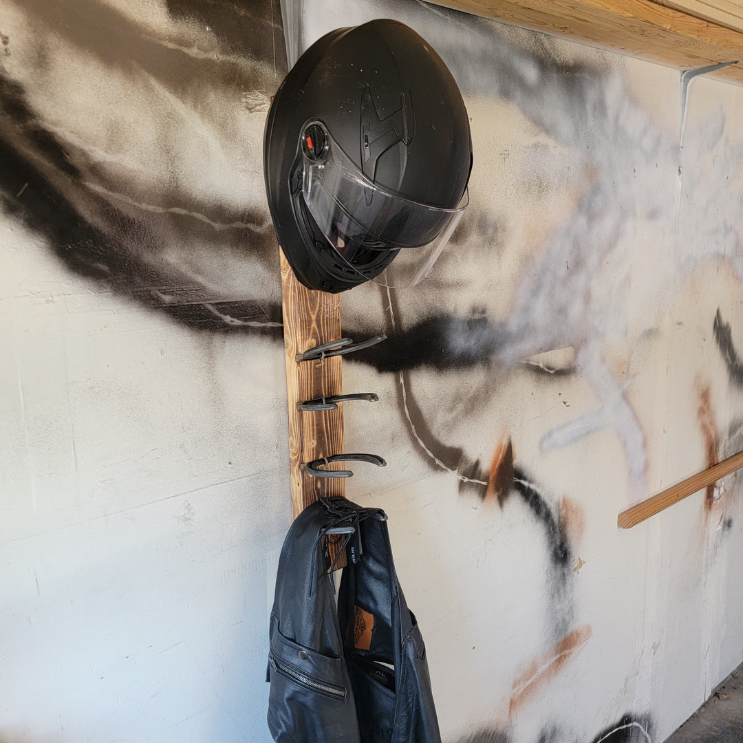 Wood motorcycle gear rack with black helmet mounted and jacket hanging below