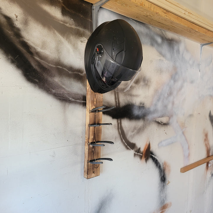 Black motorcycle helmet mounted on a wooden rack with multiple metal loops