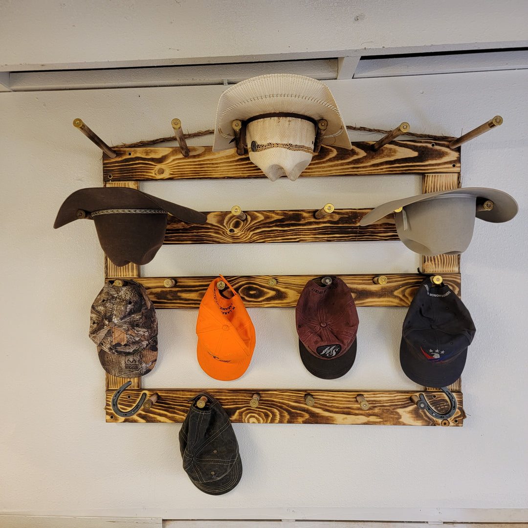 Wall-mounted wood hat rack displaying cowboy hats and several baseball caps on rails