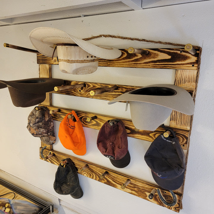 Wood hat rack holding a cream cowboy hat and several baseball caps in mixed colors