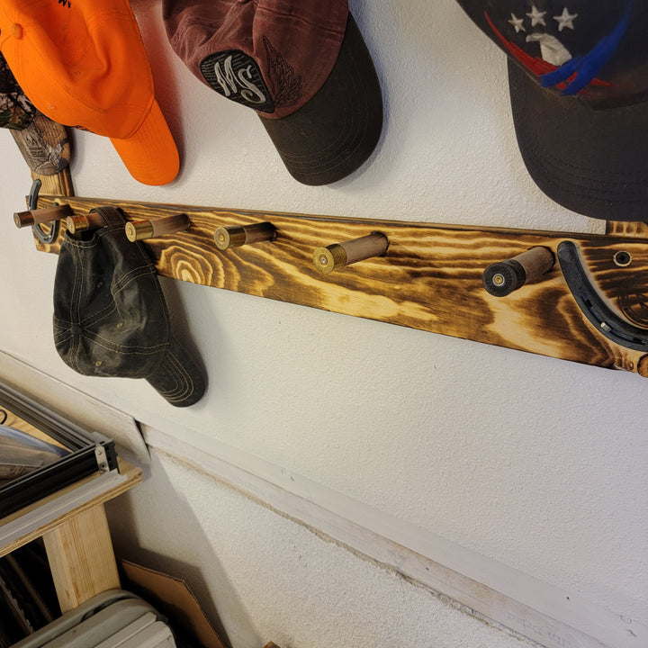Wood hat rack rail with orange, dark gray, and black baseball caps hanging