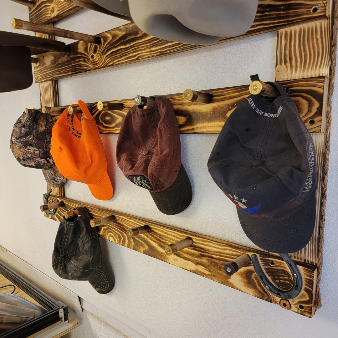 Wood hat rack with orange, brown, and dark navy baseball caps on peg rails