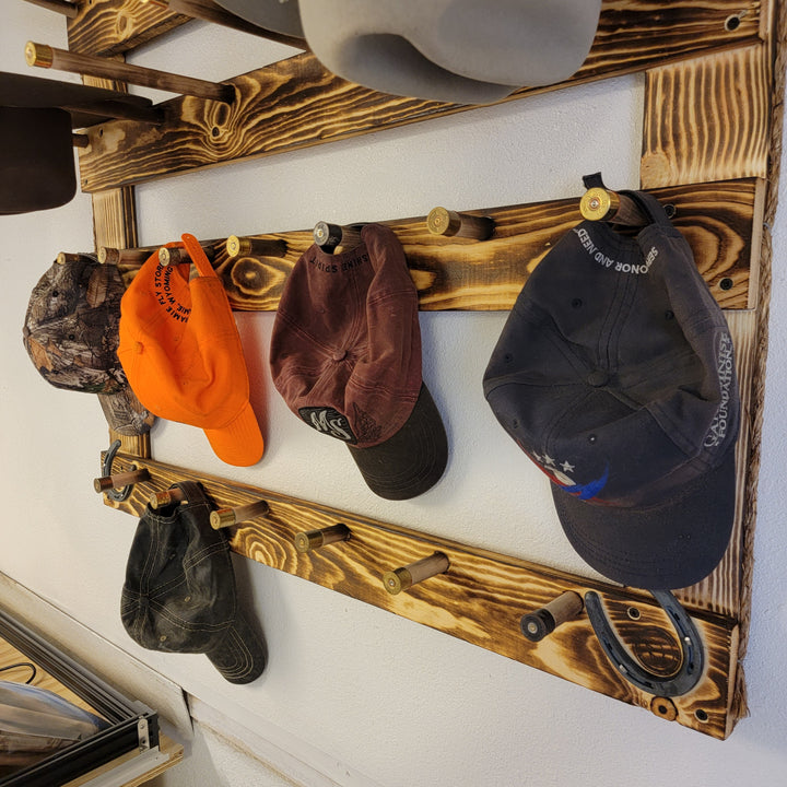 Wood hat rack with orange, brown, and dark navy baseball caps on peg rails