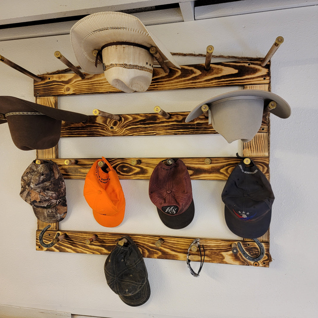 Wall-mounted wood hat rack displaying cowboy hats and assorted baseball caps on rails