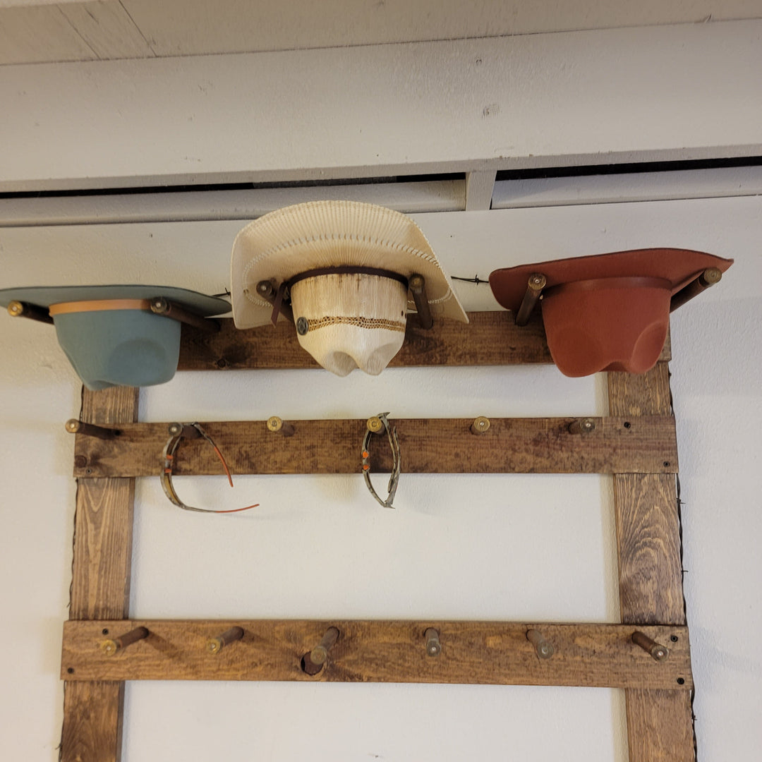 Wooden hat rack display with cream, pale blue, and rust cowboy hats and caps