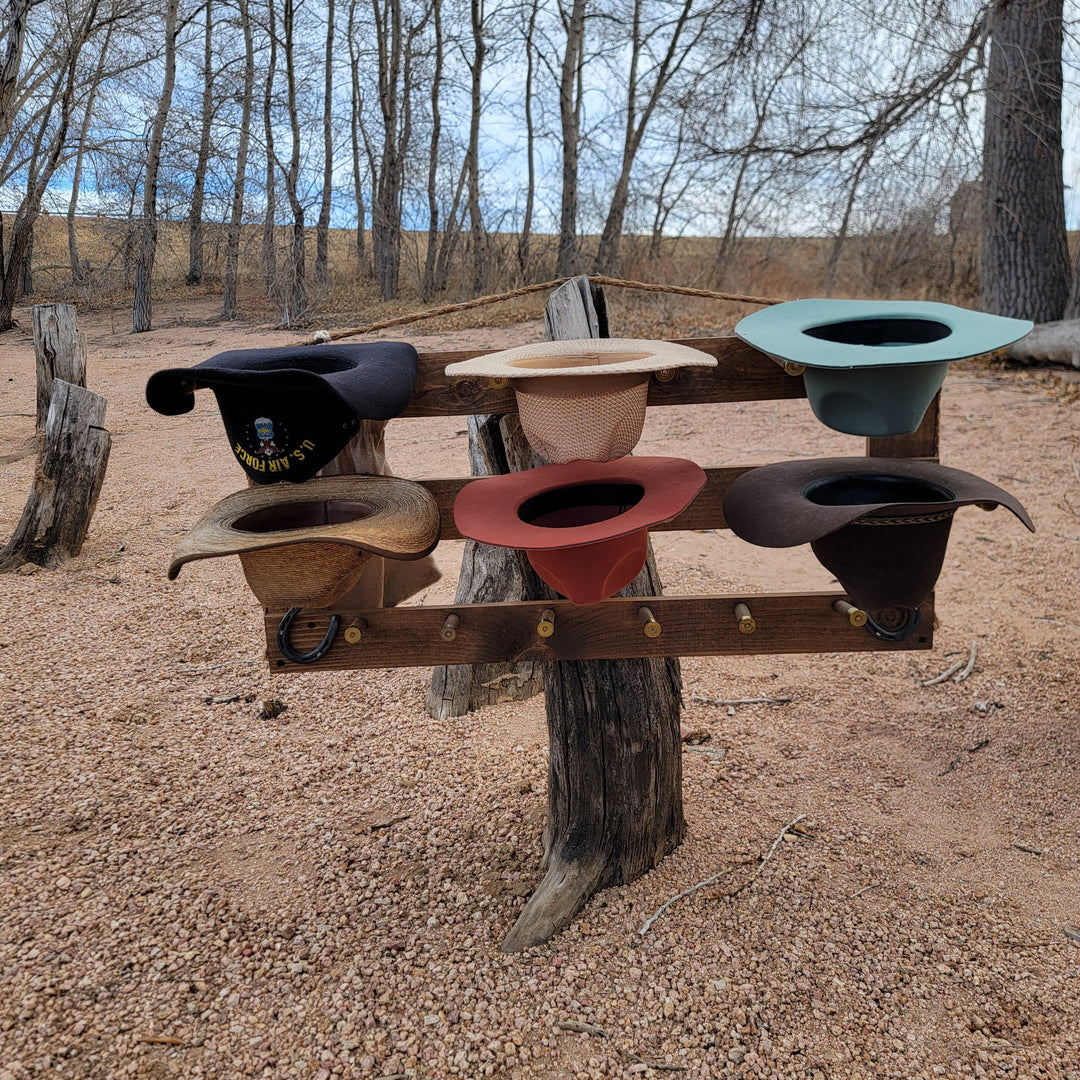 Wall-mounted western hat organizer with teal, red, cream, and dark hat slots on wood