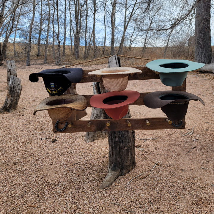 Wall-mounted western hat organizer with teal, red, cream, and dark hat slots on wood