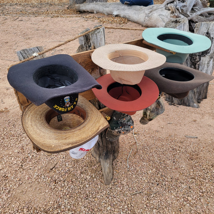 Close view of wall-hanging hat organizer with black, red, cream, teal hats and wooden pegs