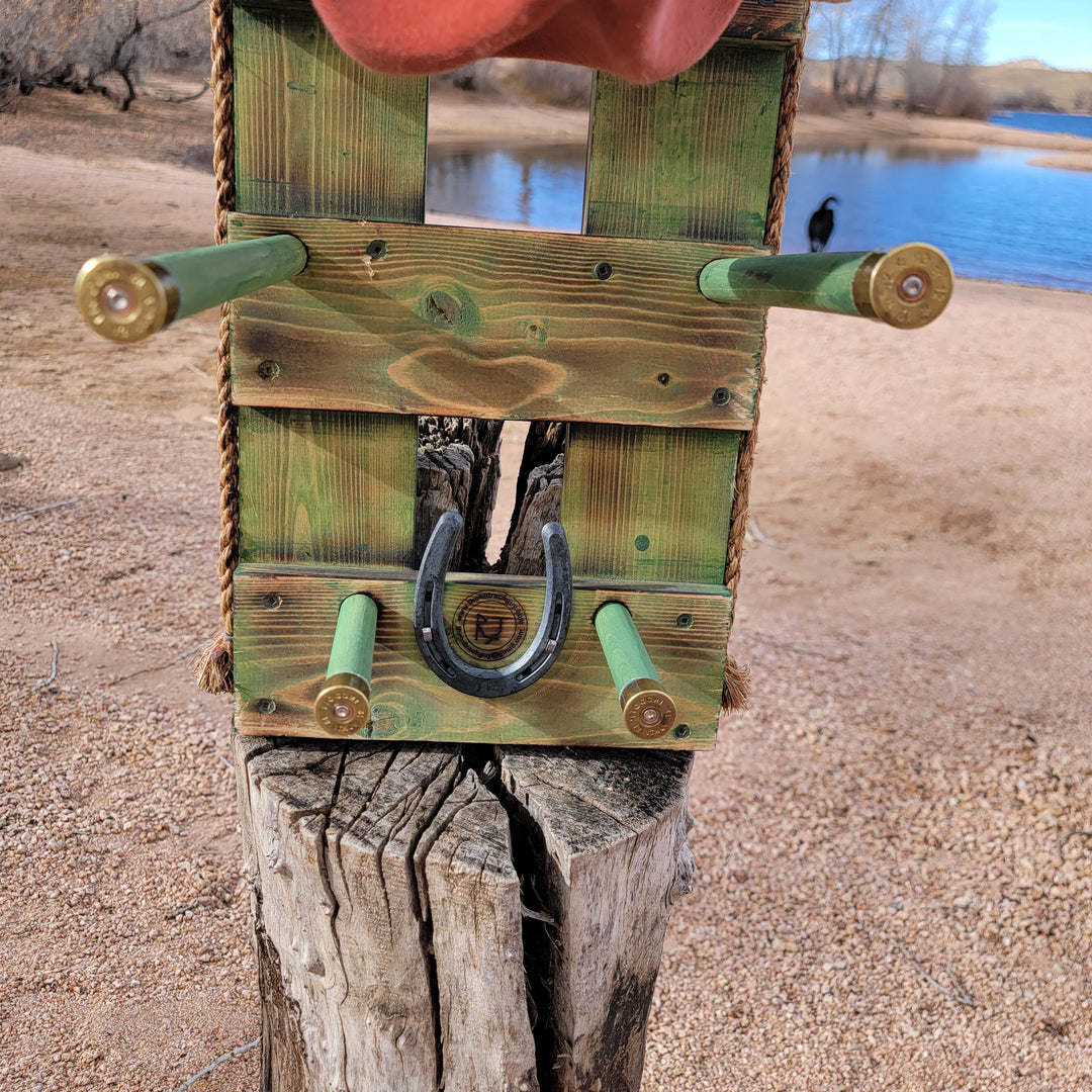 Front view of green wooden wall organizer with horseshoe emblem and hat holders