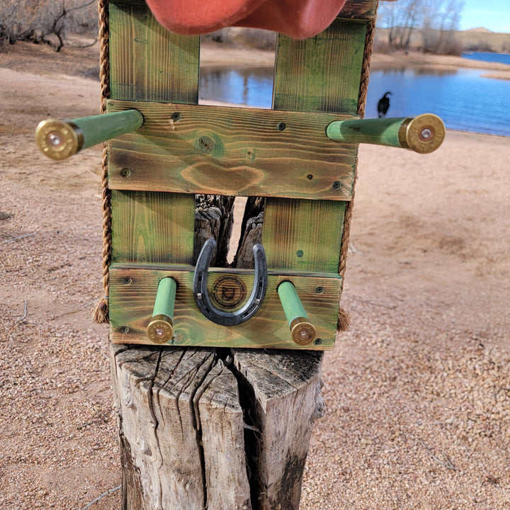 Front view of green wooden wall organizer with horseshoe emblem and hat holders