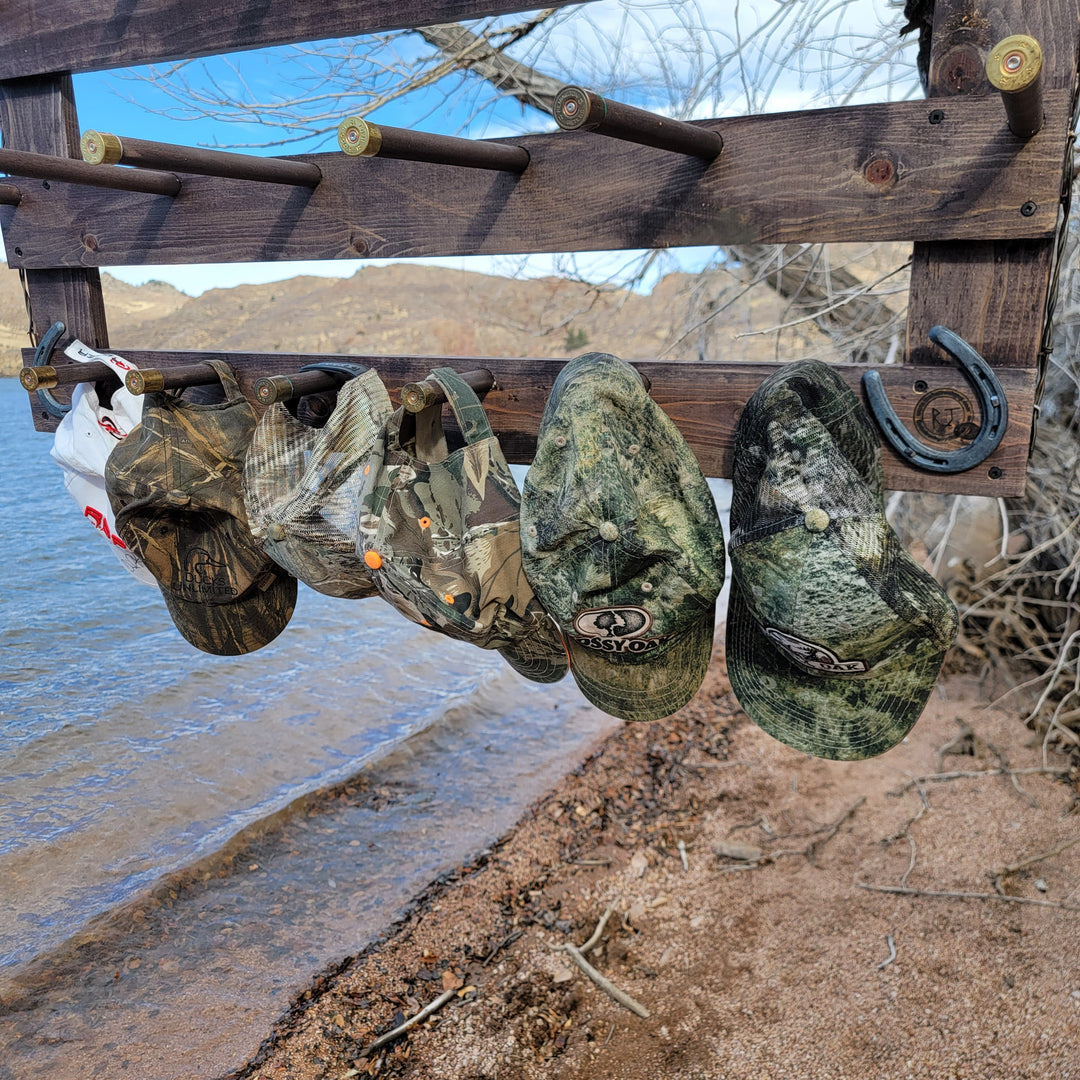Wall-hanging hat organizer with several camouflage and printed hats hanging from pegs