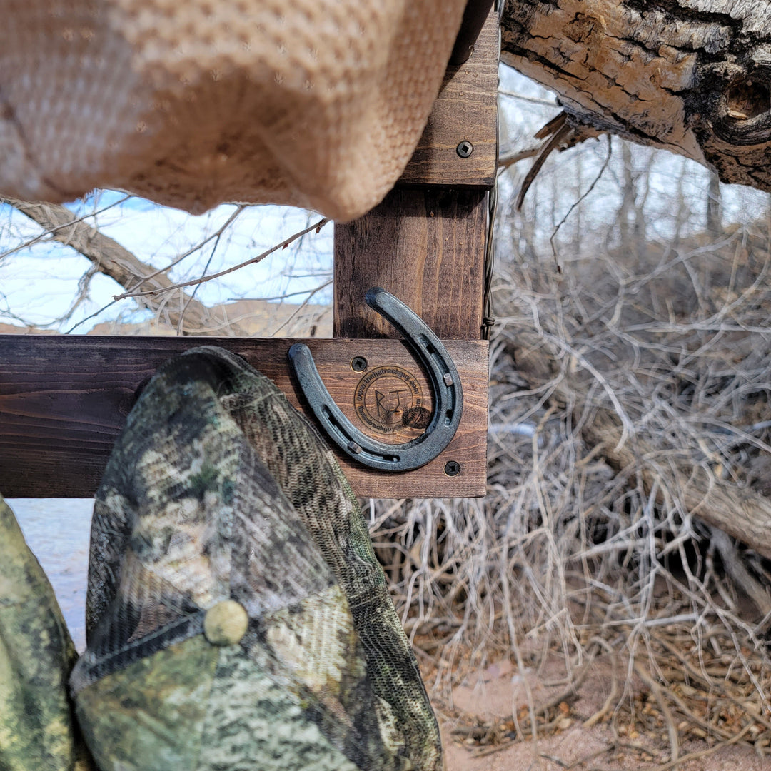 Close-up of hat organizer rail with horseshoe-style metal hooks and rustic wood