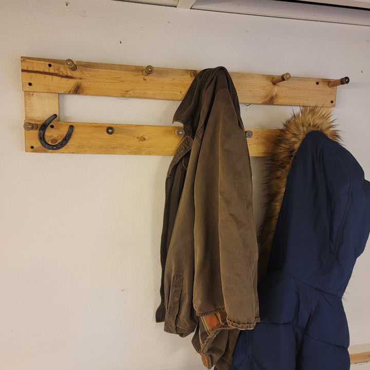 Wall-mounted coat rack displaying hanging jackets on a two-bar wooden frame