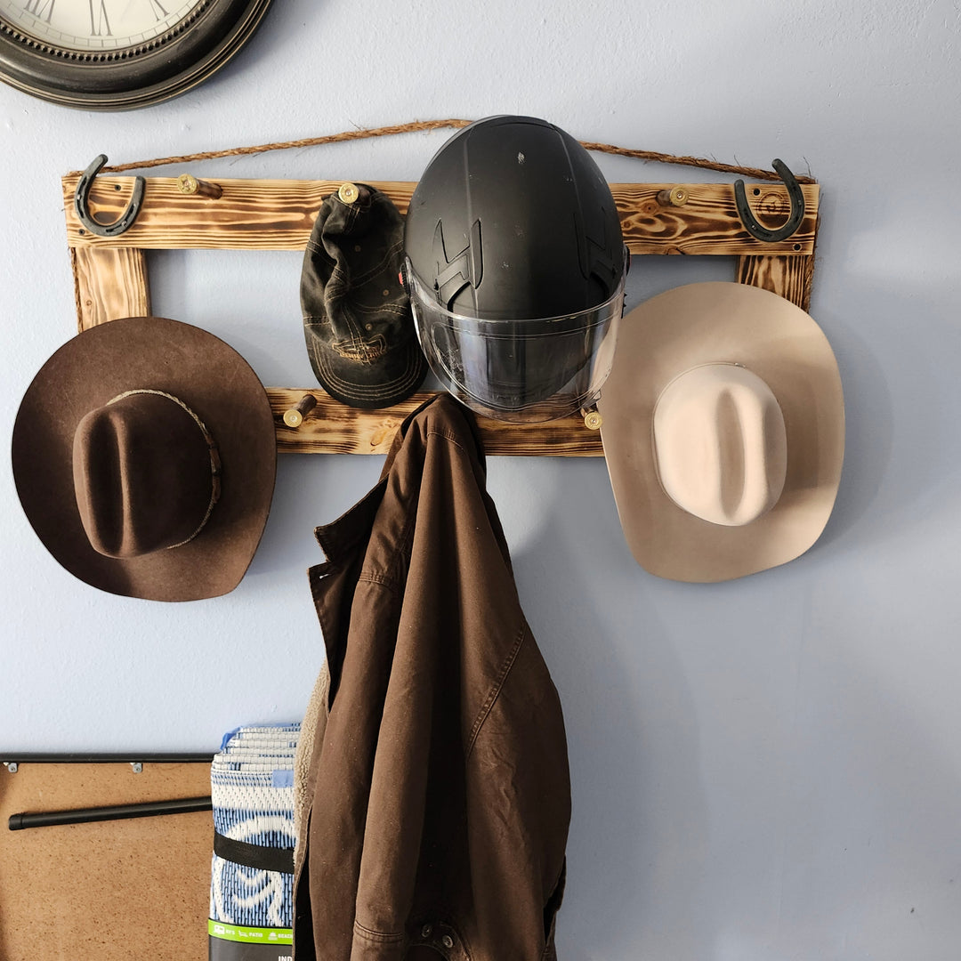 Wall-mounted heritage coat rack with curved hooks, holding hats and a coat