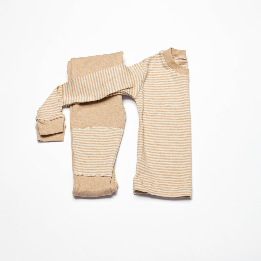 Organic baby pajama set laid flat: striped top with solid cuffed pants, beige