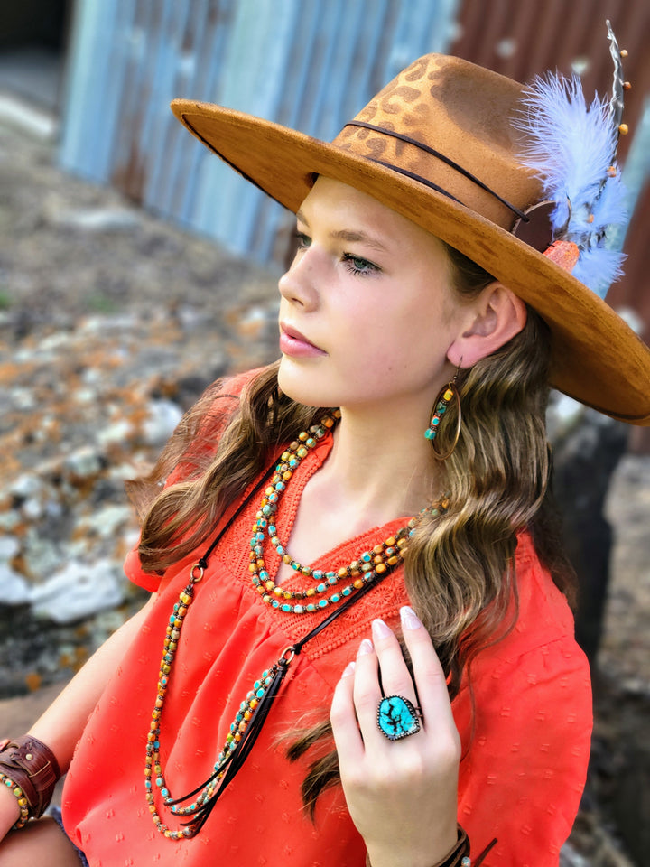 Tan wide-brim cowgirl hat with feather detail and leopard-print pattern, side view