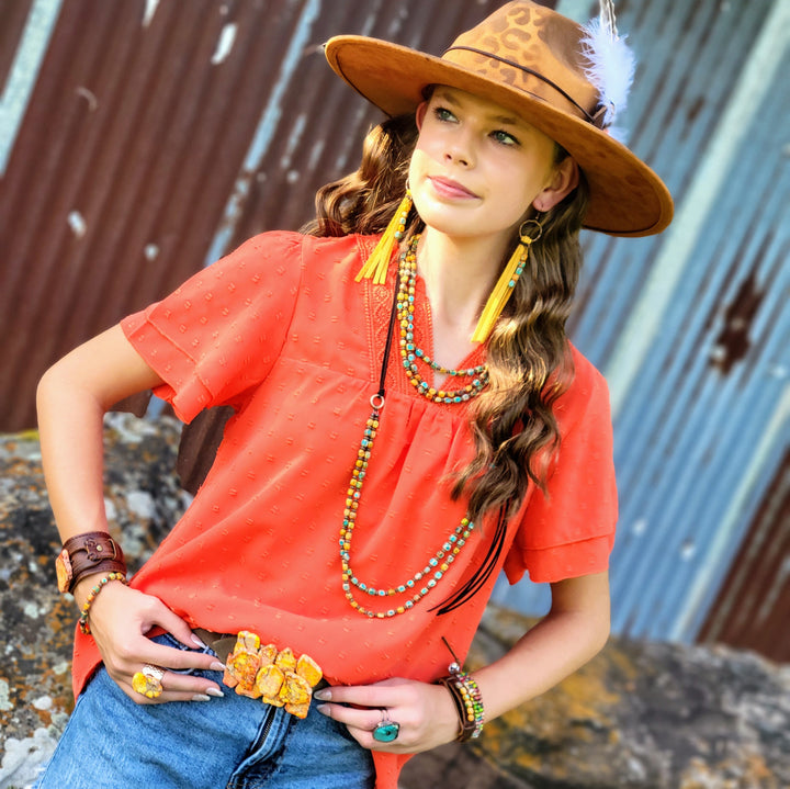 Tan leopard-print cowgirl hat with feather accent, worn by model with coral top