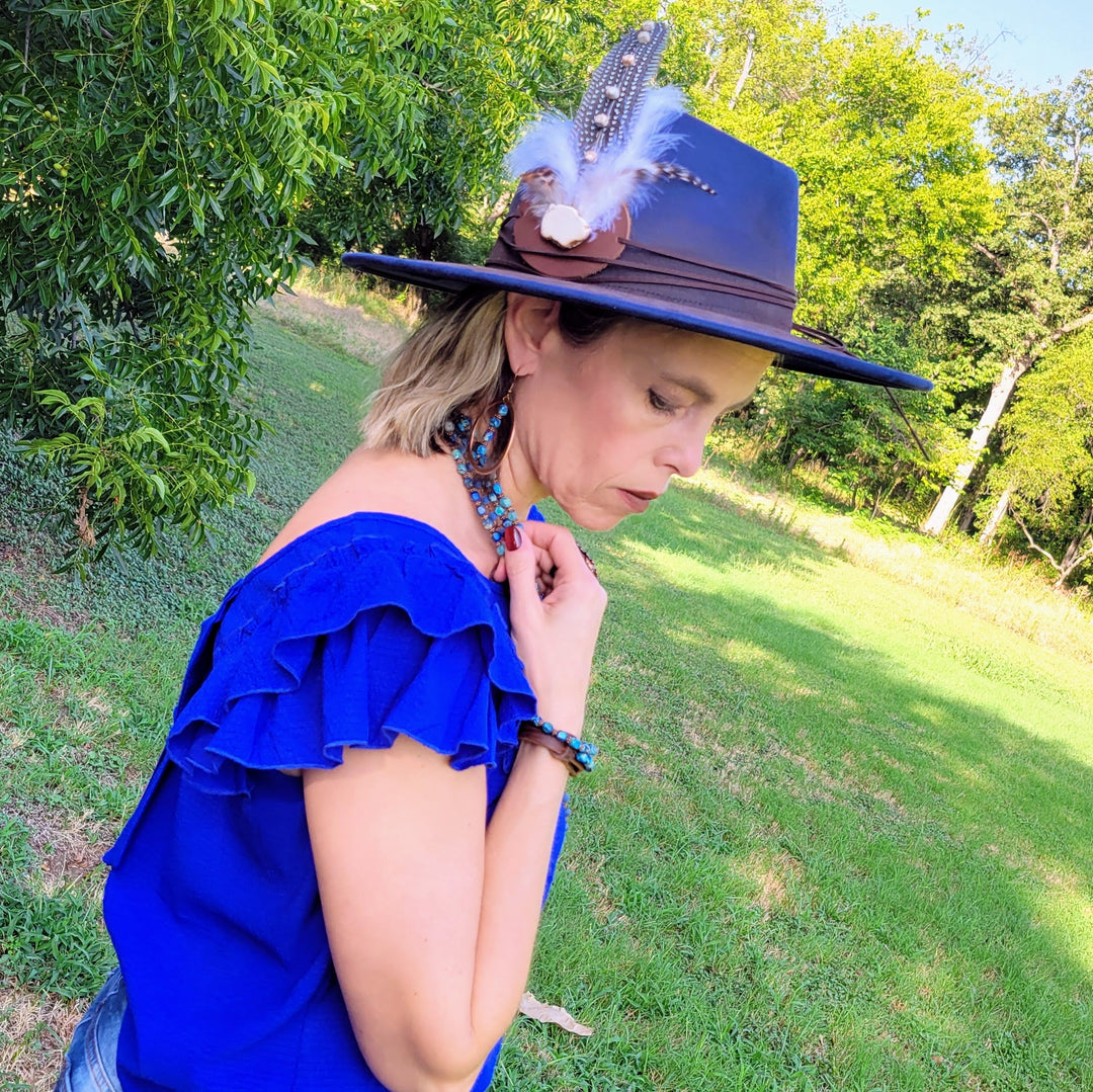 Blue cowgirl hat with brown band, worn by woman