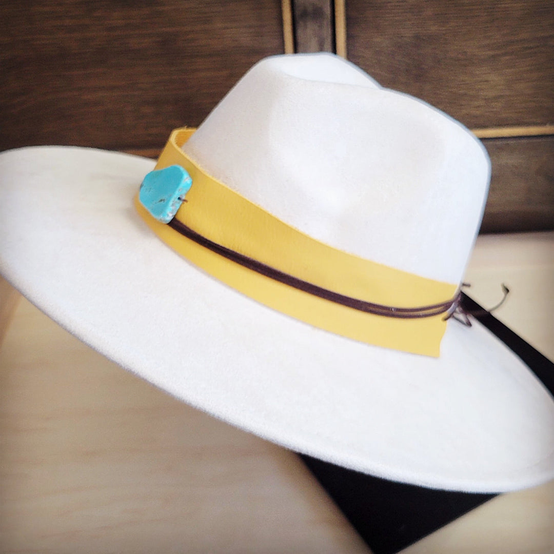 Side view of wide-brim white felt hat with mustard leather band and turquoise accent