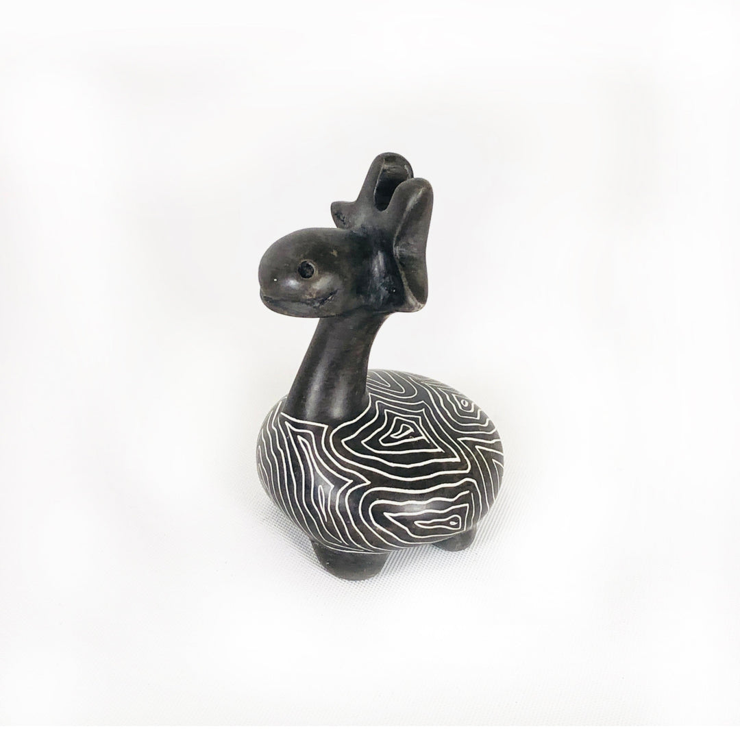Soapstone giraffe figurine with dark body and white wavy stripe pattern, facing forward-left