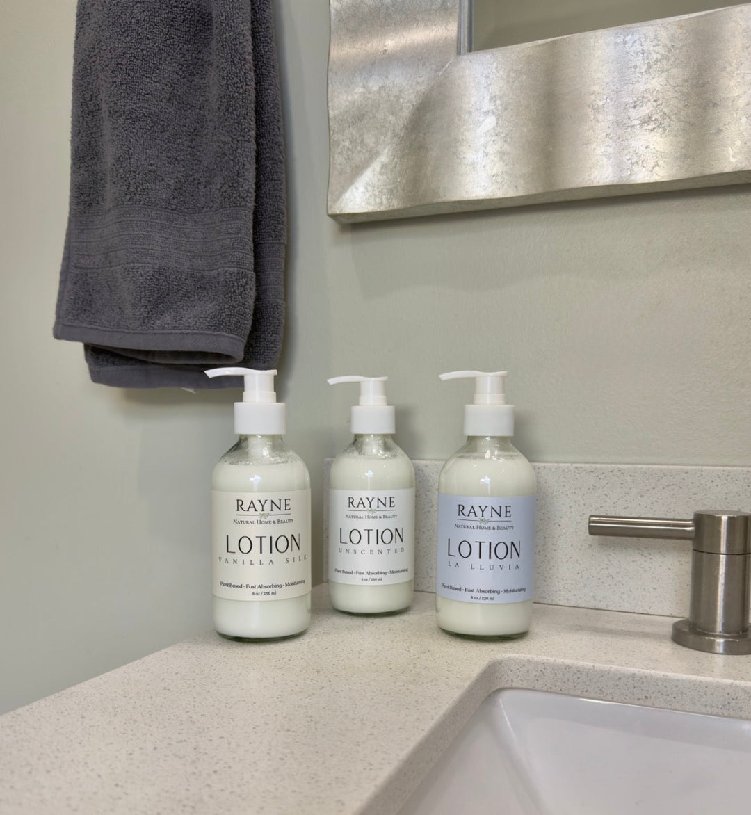 Three moisturizing body lotion pump bottles on vanity counter with towel nearby.