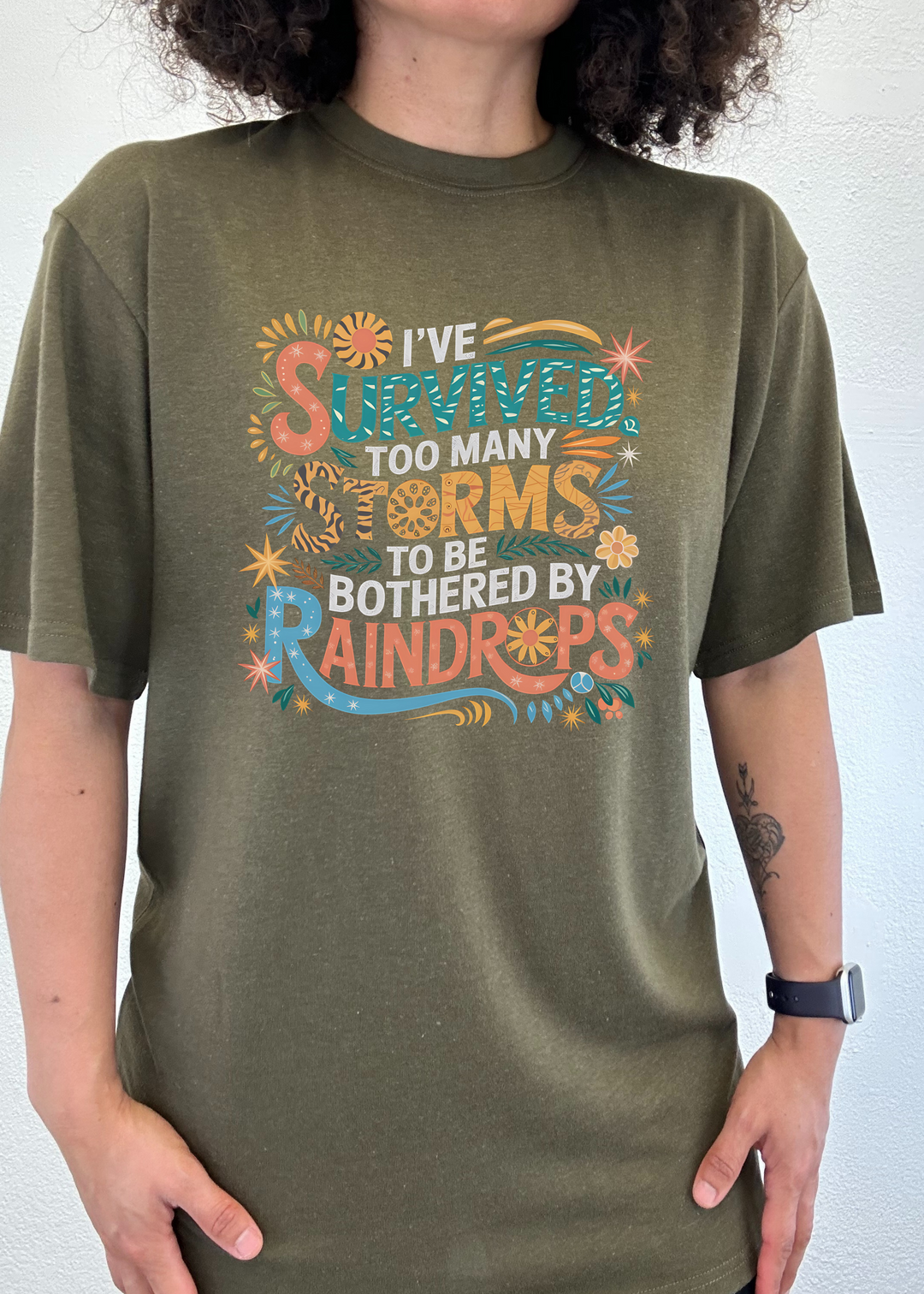 Unisex graphic t-shirt, olive green, colorful storm-themed front print.