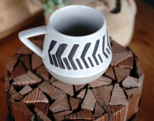 Two-toned geometric abstract ceramic mug, front view with black chevron lines