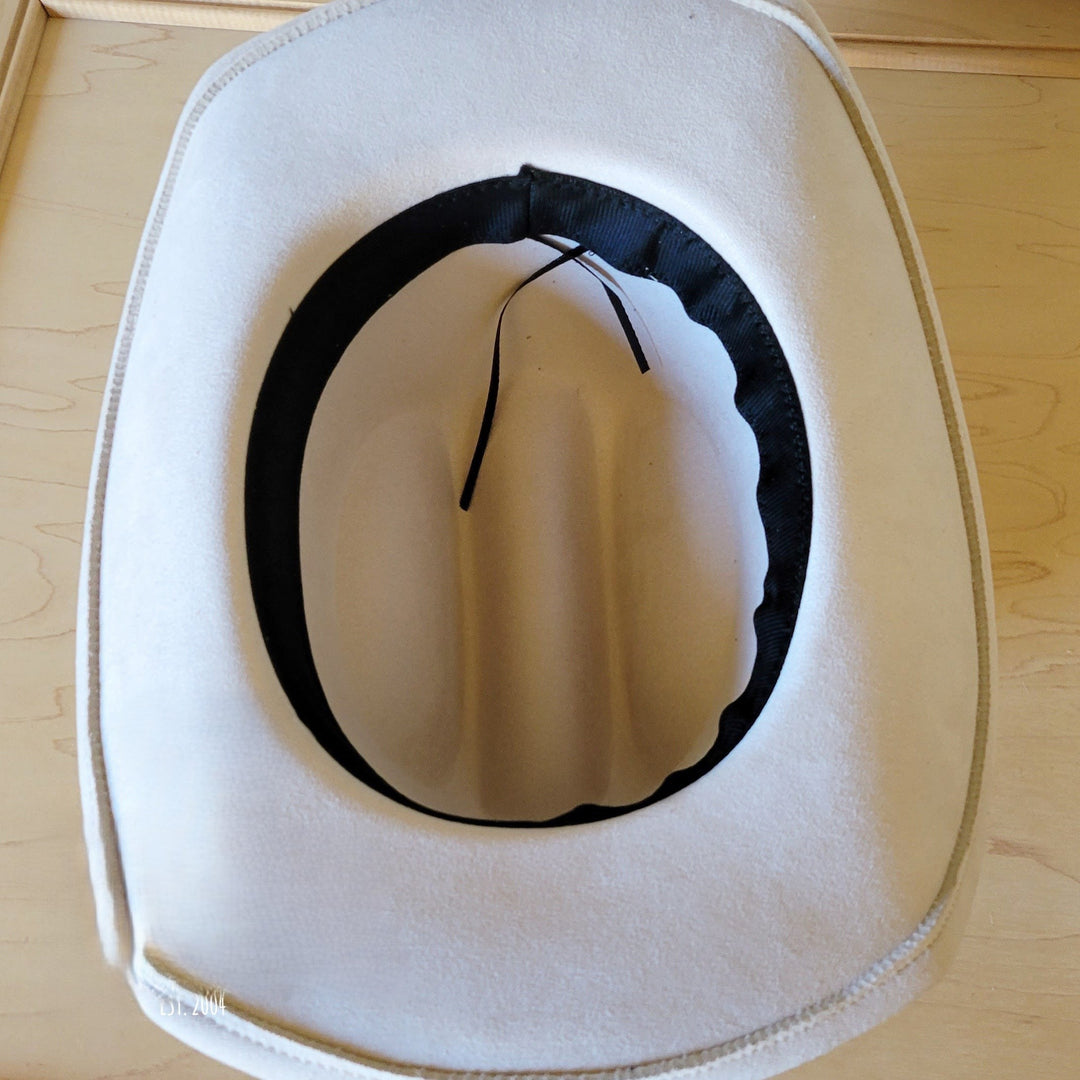 Inside view of wide-brim white felt hat with black inner band and tie ends