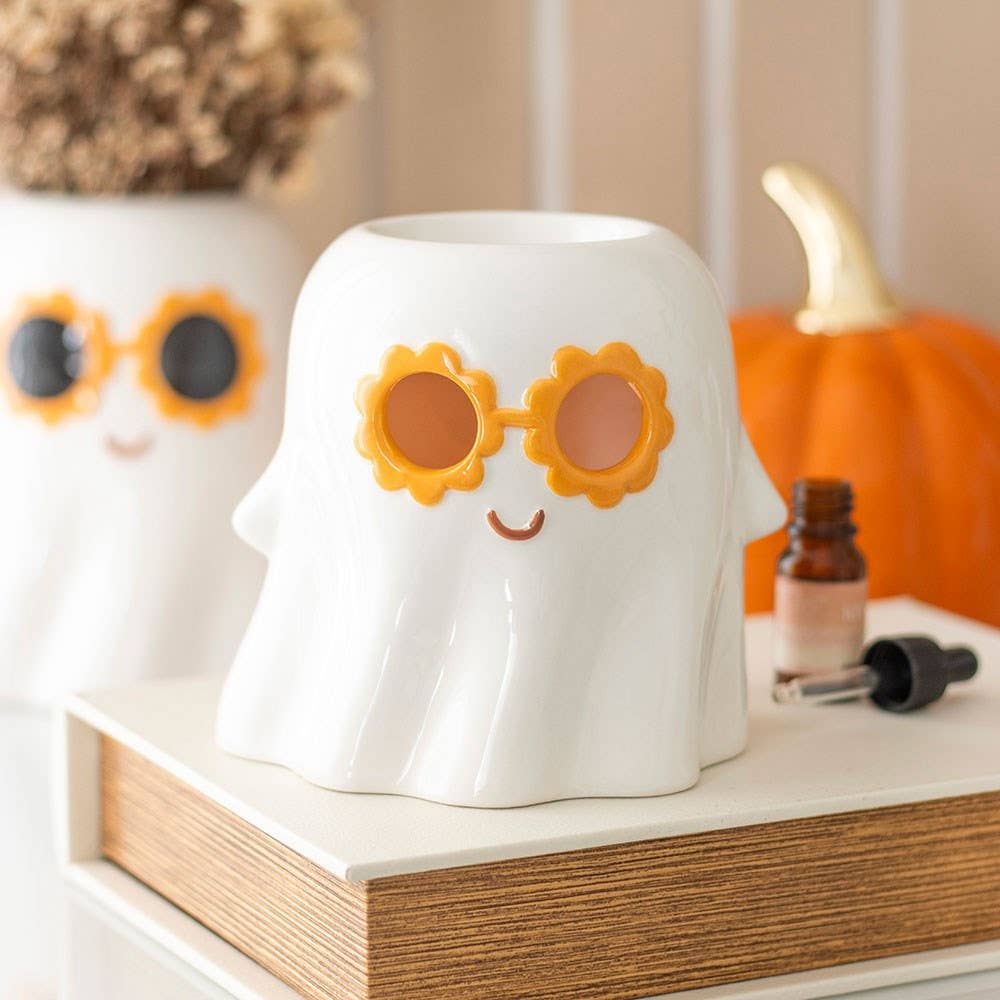 White ghost-shaped wax warmer with orange flower glasses and smiling face.