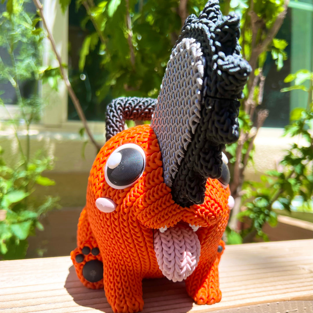 Knitted orange plush with black yarn mane, gray button eye, white muzzle patch, seated pose