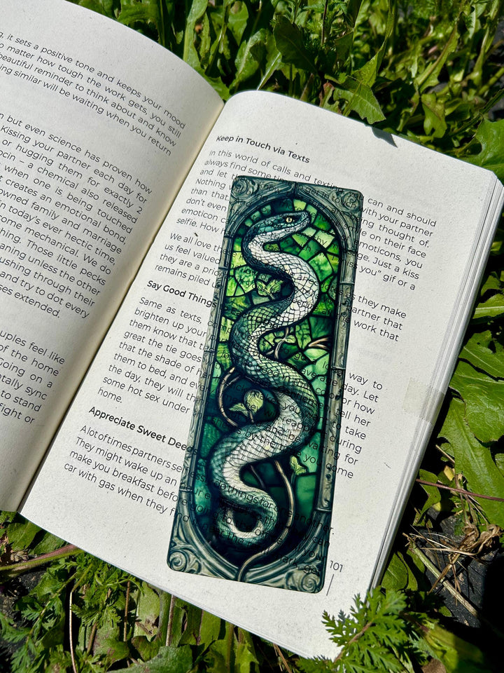 Teal serpent stained-glass bookmark with ornate pattern between open pages