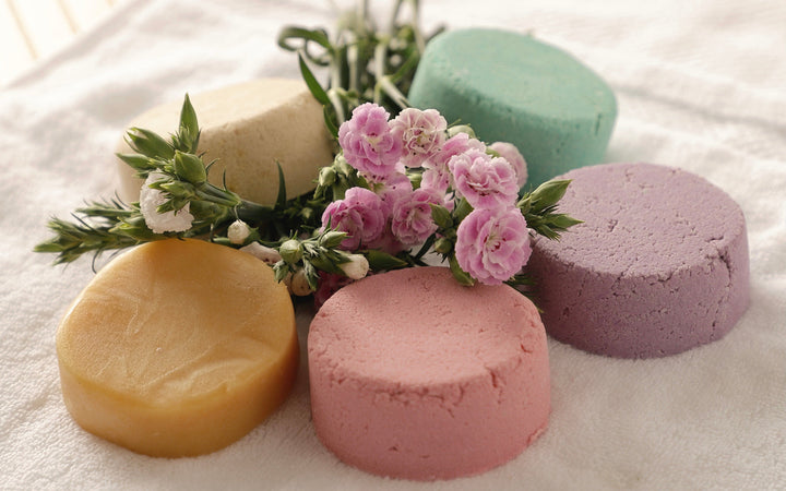 Round shampoo bars in beige, golden, pink, and lavender with small flowers