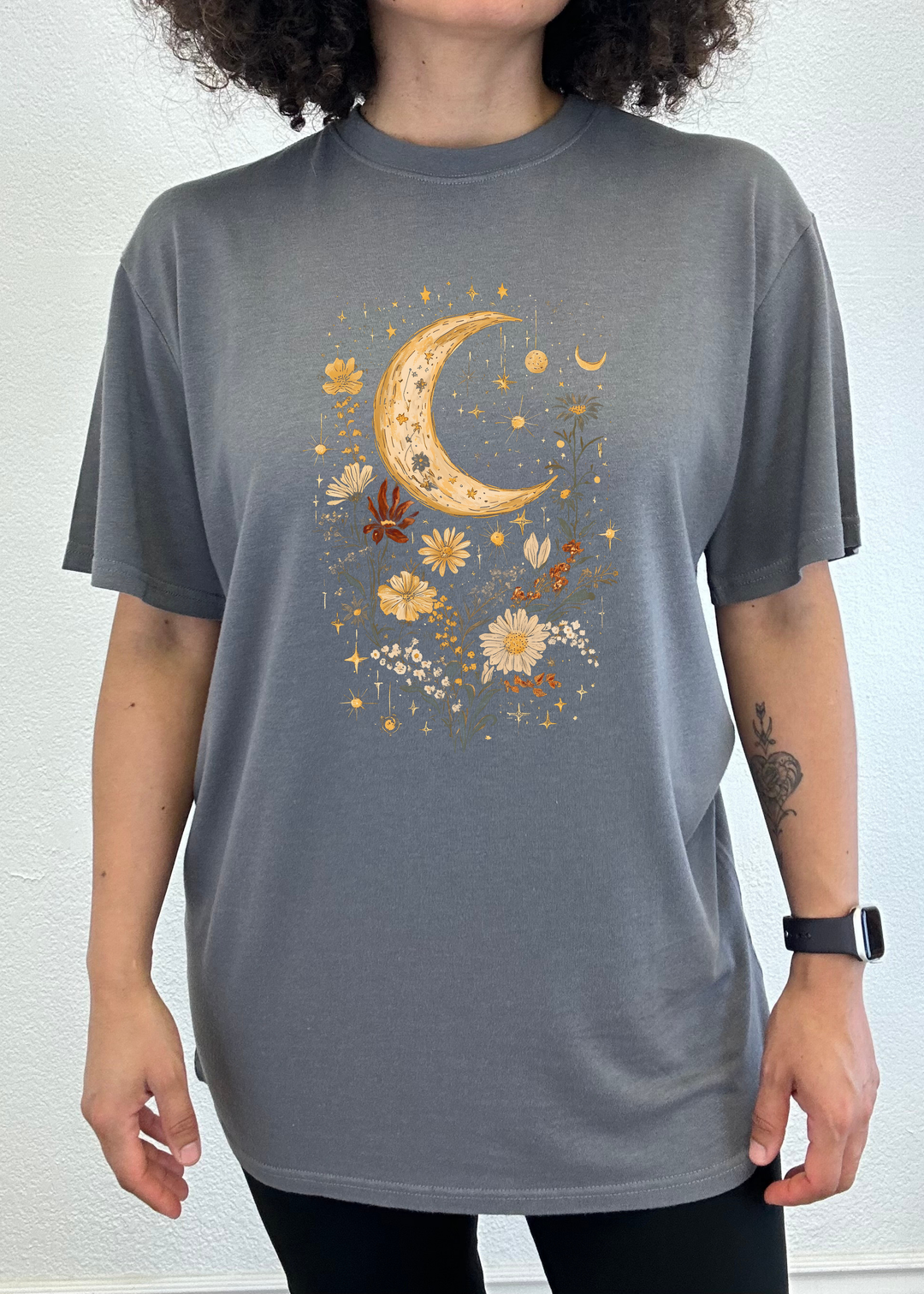 Unisex graphic T-shirt in charcoal gray with gold crescent moon and flower artwork.