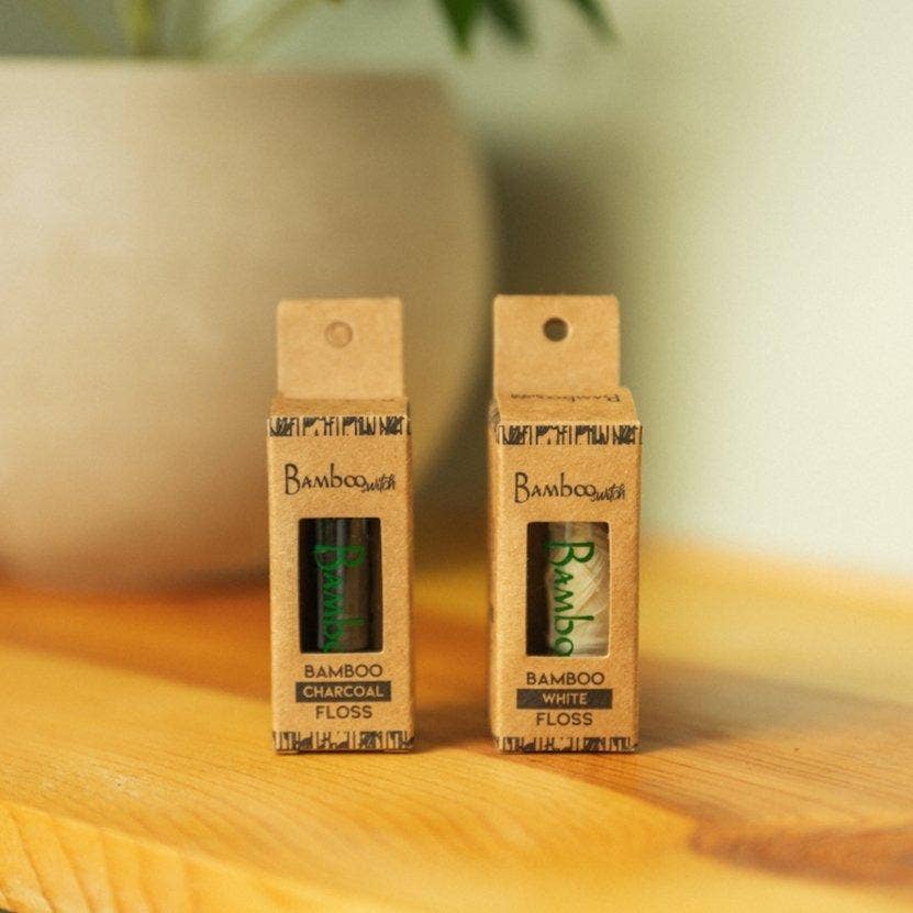 Charcoal and white bamboo floss cardboard packs standing side by side
