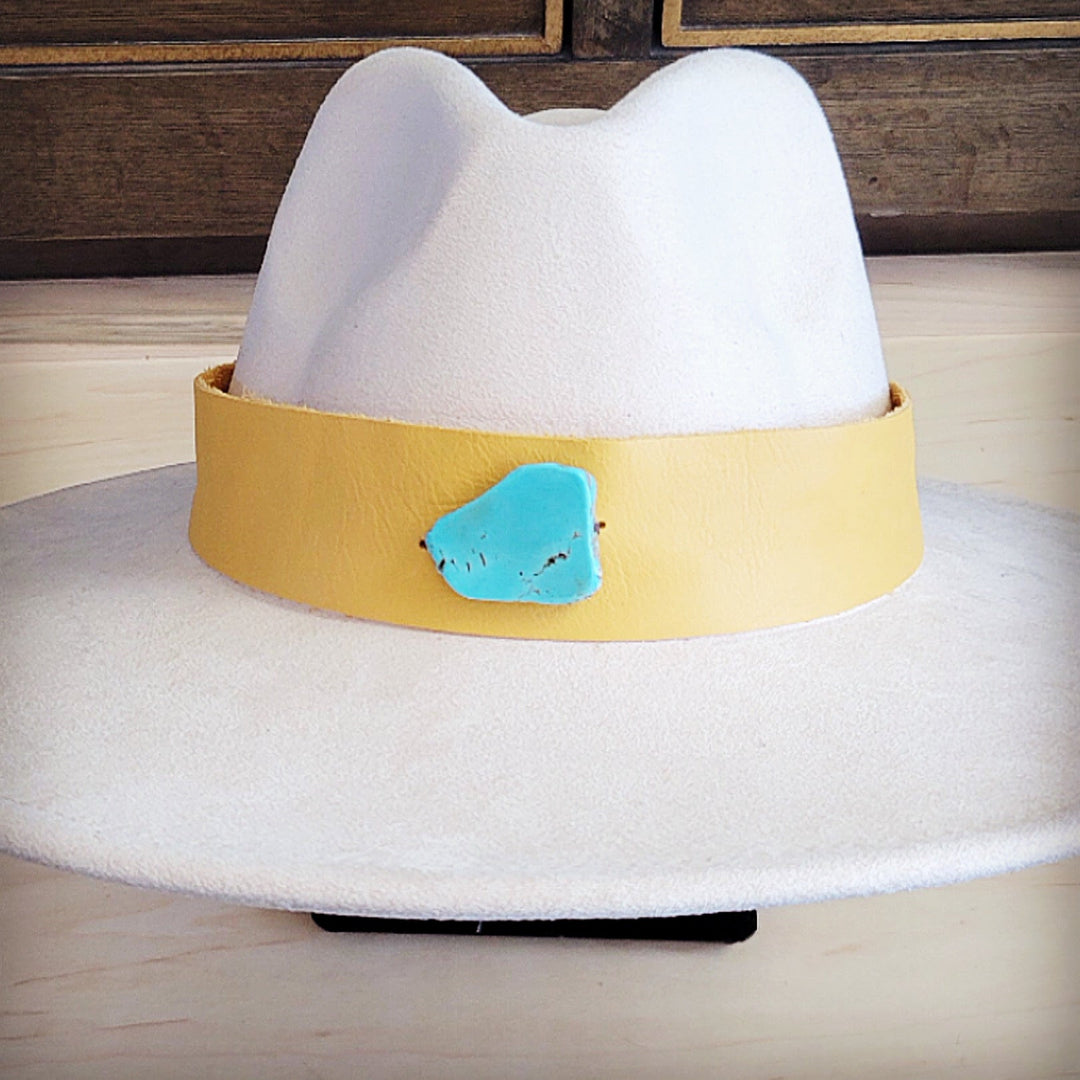 Front view of wide-brim white felt hat with mustard leather band and turquoise accent