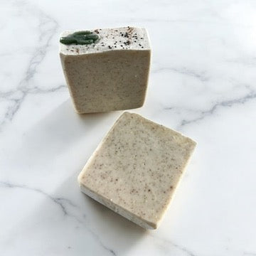 Handmade soap bar with speckled surface and small green swirl, rectangular
