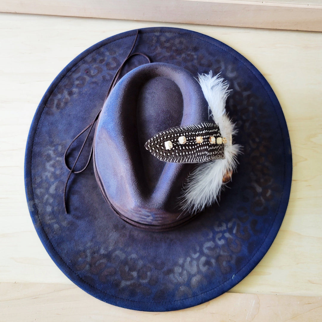 Navy blue leopard-print cowgirl hat with feather-and-bead accent hatband